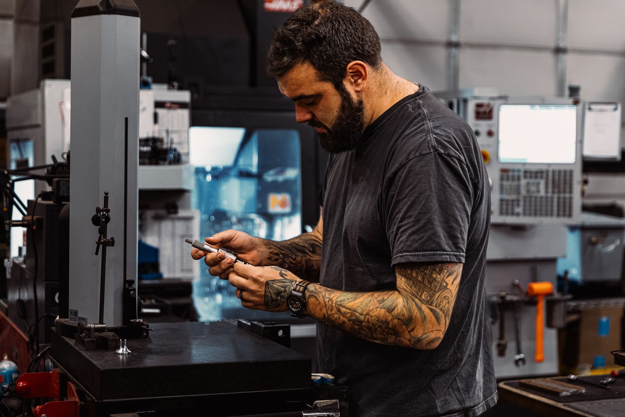Programador CNC conferindo uma peça ao lado da máquina